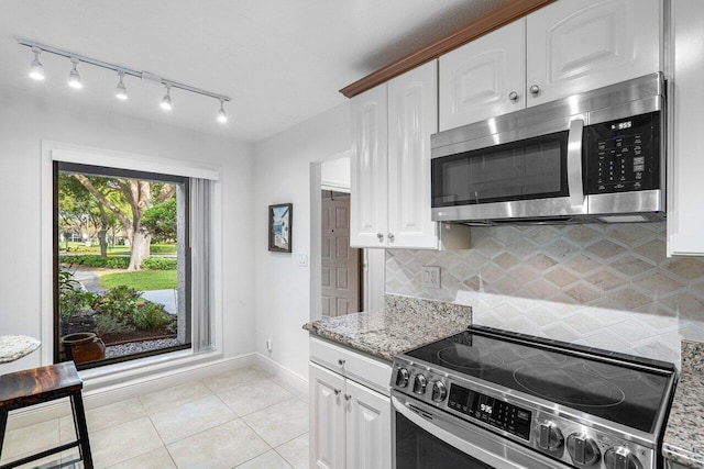 kitchen with light stone counters, appliances with stainless steel finishes, light tile patterned floors, and white cabinetry