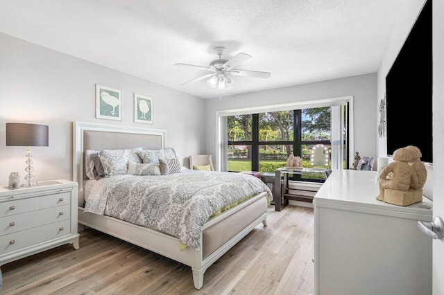 bedroom featuring ceiling fan, light wood-type flooring, and a textured ceiling