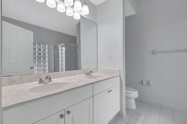 bathroom featuring tile patterned flooring, vanity, a shower with shower door, and toilet