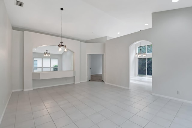 tiled empty room featuring a chandelier