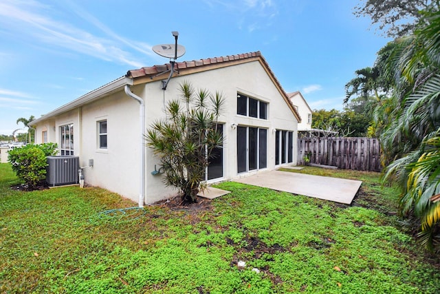 rear view of house featuring a lawn, cooling unit, and a patio