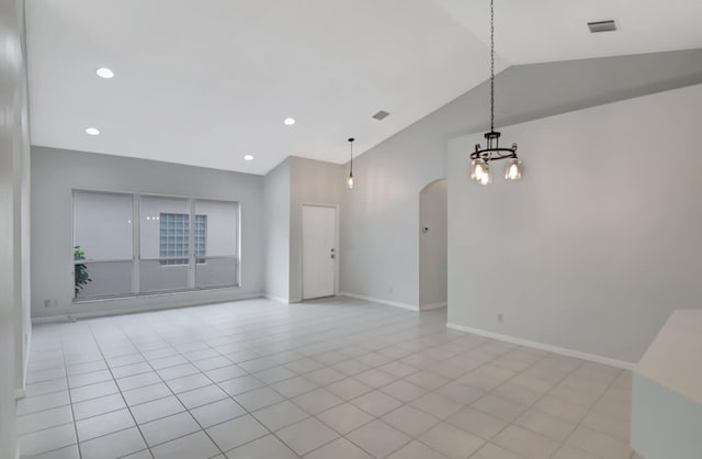 tiled empty room featuring high vaulted ceiling and a chandelier