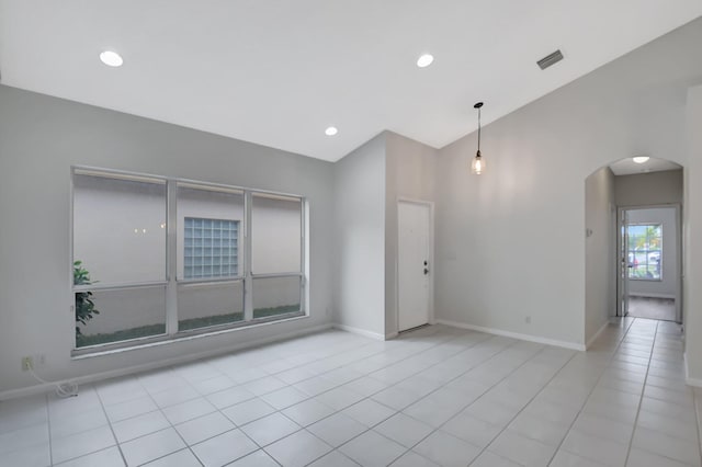 tiled spare room featuring vaulted ceiling