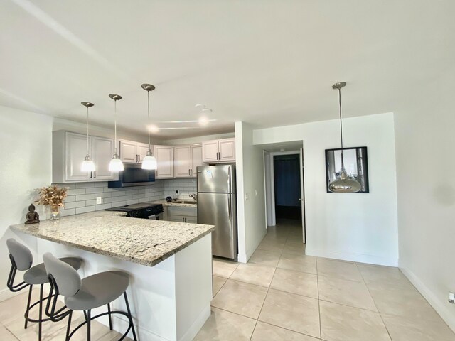 kitchen with pendant lighting, kitchen peninsula, decorative backsplash, and appliances with stainless steel finishes