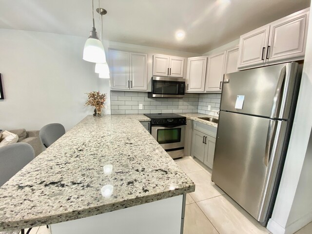 kitchen featuring decorative light fixtures, kitchen peninsula, backsplash, appliances with stainless steel finishes, and white cabinetry