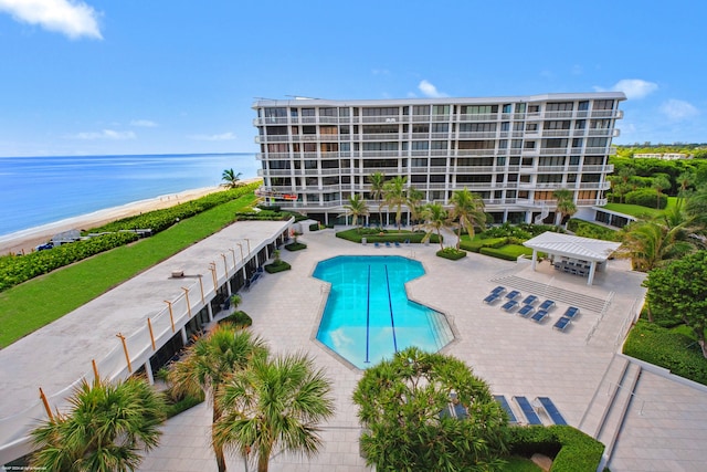 view of swimming pool with a view of the beach, a patio, and a water view