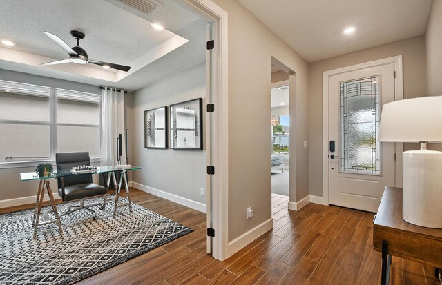 office with ceiling fan, wood-type flooring, a tray ceiling, and a textured ceiling