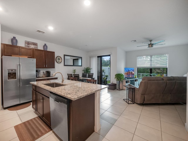 kitchen with appliances with stainless steel finishes, ceiling fan, a kitchen island with sink, sink, and light tile patterned floors