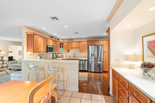 kitchen featuring backsplash, crown molding, a breakfast bar area, and stainless steel appliances