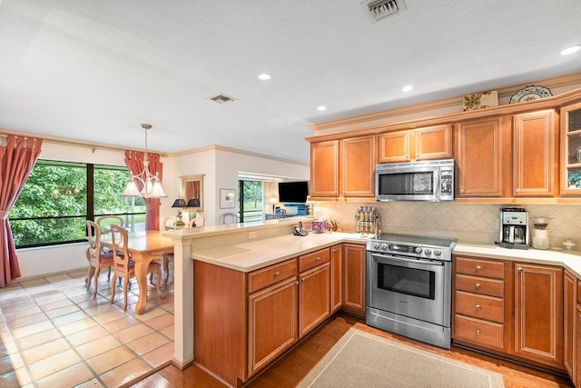 kitchen featuring appliances with stainless steel finishes, tasteful backsplash, a notable chandelier, decorative light fixtures, and kitchen peninsula