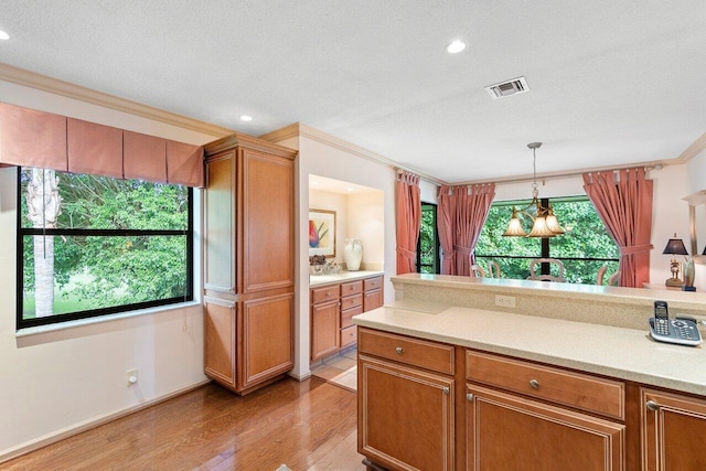 kitchen featuring crown molding, pendant lighting, a textured ceiling, and light wood-type flooring