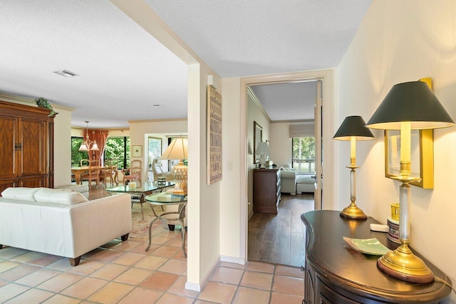 hallway featuring ornamental molding, light tile patterned floors, and a textured ceiling