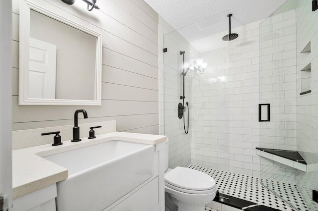 bathroom with wood walls, walk in shower, toilet, vanity, and a textured ceiling