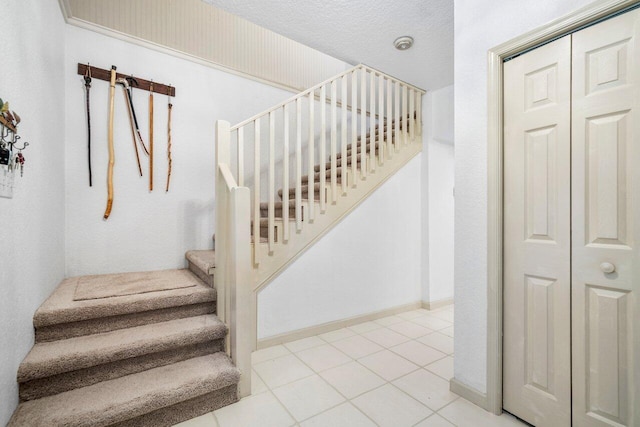 stairway with tile patterned floors and a textured ceiling