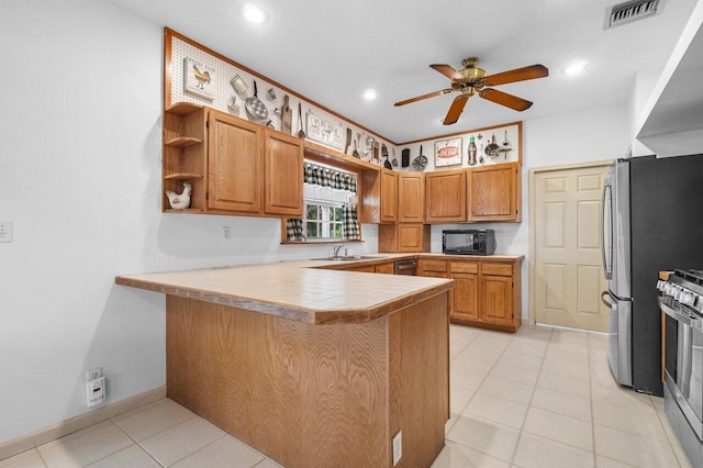 kitchen with ceiling fan, stainless steel appliances, sink, light tile patterned flooring, and kitchen peninsula