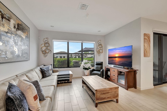 living room featuring visible vents, baseboards, and light wood finished floors