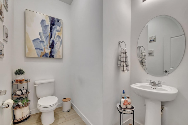 bathroom with a sink, baseboards, toilet, and wood finished floors