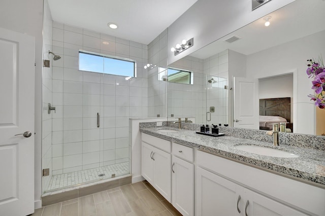 ensuite bathroom featuring visible vents, double vanity, a sink, a shower stall, and connected bathroom