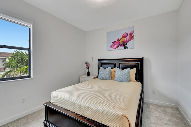 bedroom with light colored carpet and baseboards