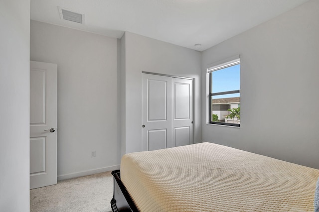 bedroom featuring a closet, visible vents, light colored carpet, and baseboards