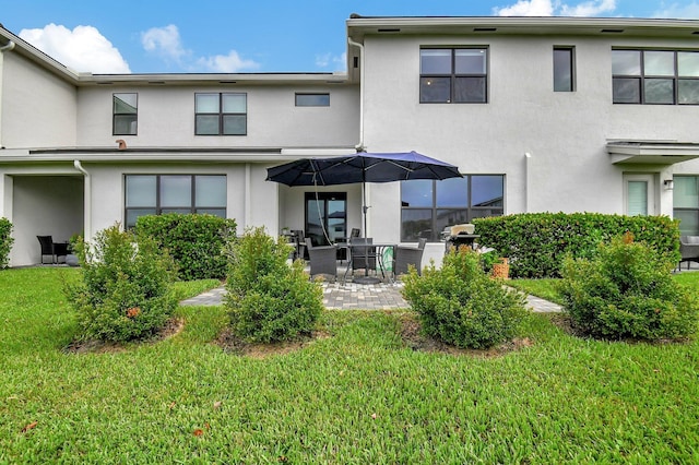 back of property featuring stucco siding, a lawn, and a patio