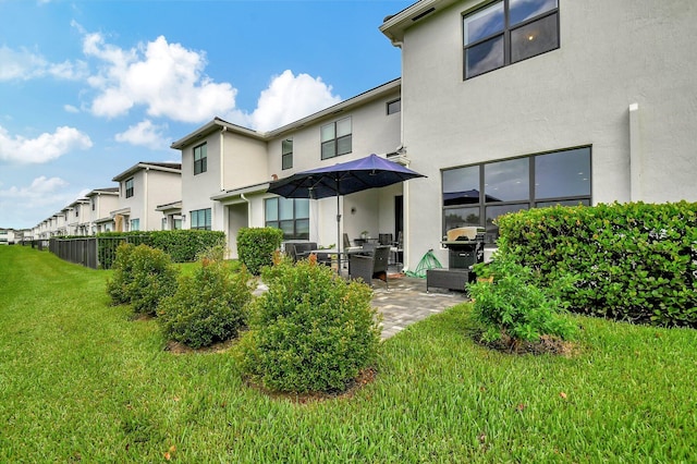 back of house with a yard, stucco siding, and a patio