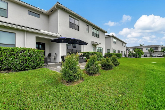 back of property featuring a patio and a lawn