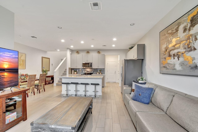 living room with visible vents, stairway, and light wood-style floors