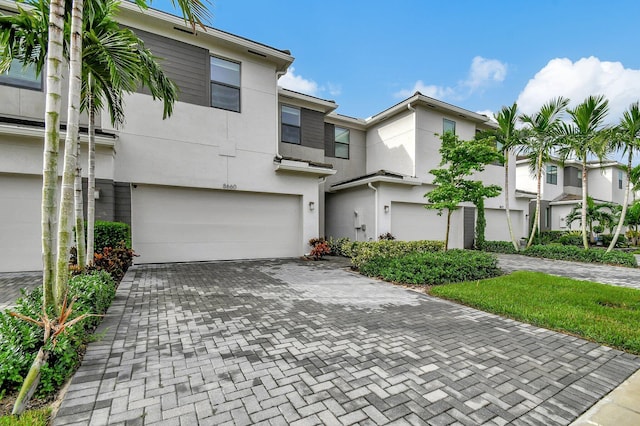 townhome / multi-family property featuring decorative driveway, an attached garage, and stucco siding