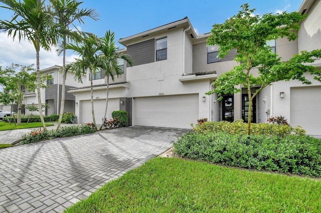 view of front facade with decorative driveway, a garage, and stucco siding