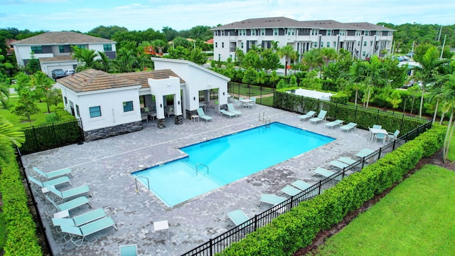 pool featuring a patio area, a yard, and fence