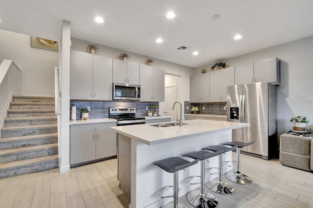 kitchen with visible vents, a sink, a kitchen breakfast bar, stainless steel appliances, and light countertops