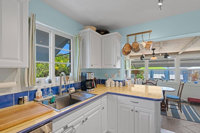 kitchen featuring light tile patterned floors, white cabinets, a sink, and light countertops