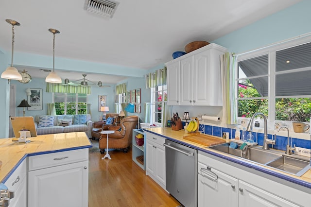 kitchen featuring visible vents, white cabinets, dishwasher, light wood-style floors, and a sink