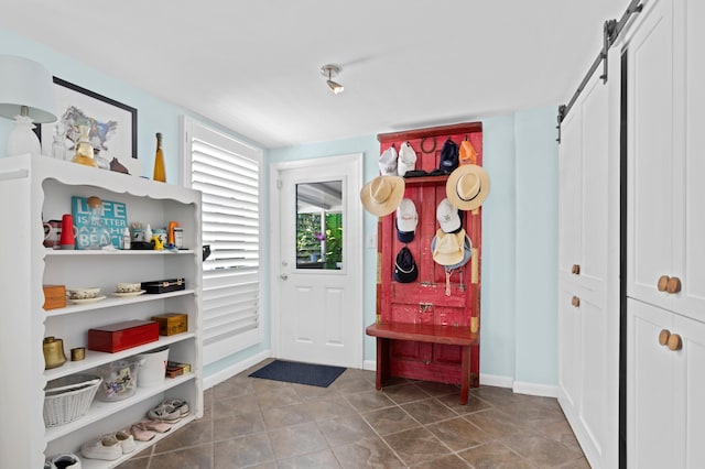 mudroom with tile patterned floors, baseboards, and a barn door