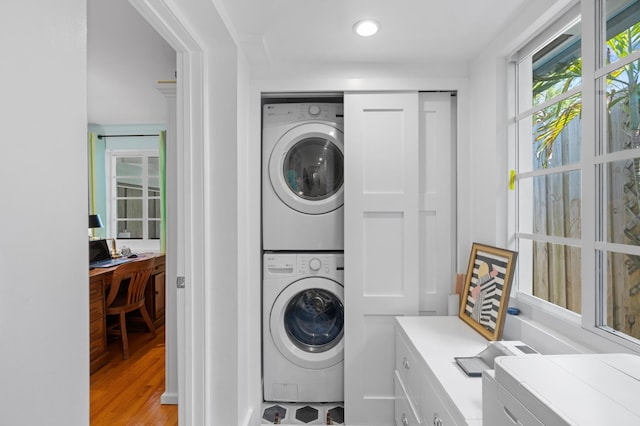 washroom with stacked washing maching and dryer and light hardwood / wood-style flooring