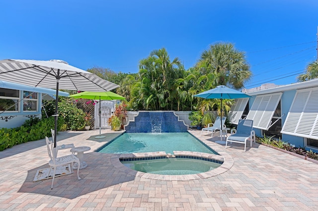 view of swimming pool with a patio area, fence, and a pool with connected hot tub