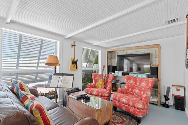 living room with finished concrete floors, visible vents, and beamed ceiling