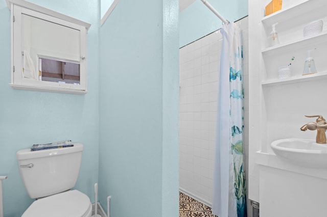 bathroom featuring toilet, a sink, and tiled shower