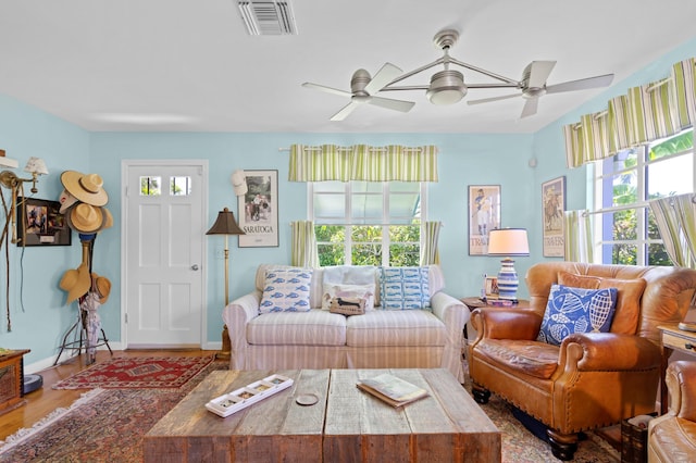 living area with baseboards, visible vents, a wealth of natural light, and wood finished floors