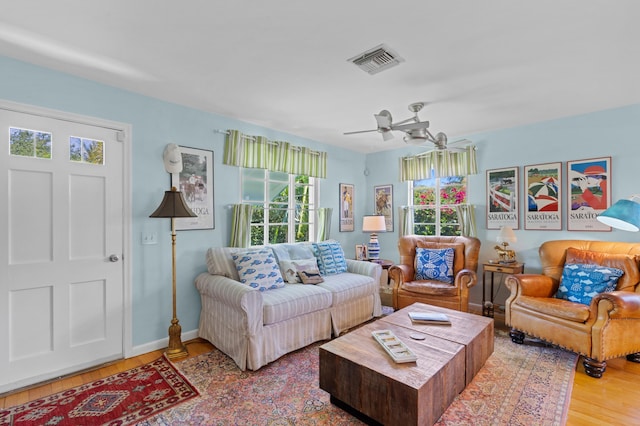 living room with ceiling fan, wood finished floors, visible vents, and baseboards