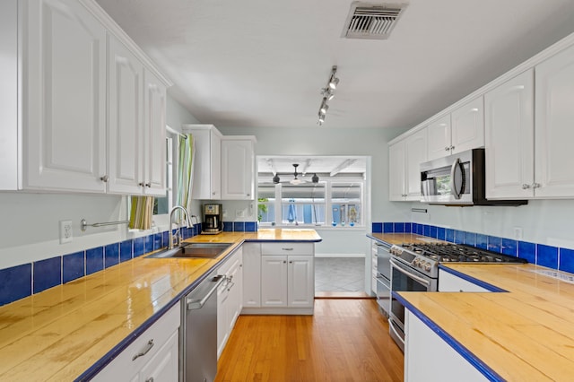 430 N Ocean Breeze, Lake Worth Beach, FL 33460 - kitchen with ceiling fan, stainless steel appliances, light wood-style floors, white cabinetry, and rail lighting