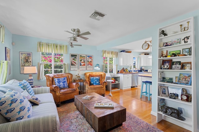 living area featuring visible vents, plenty of natural light, light wood finished floors, and ceiling fan