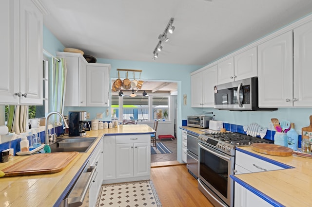 kitchen with stainless steel appliances, light countertops, a healthy amount of sunlight, and white cabinets