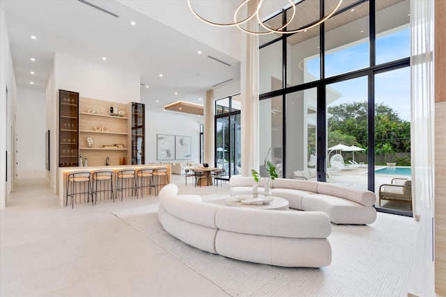 living room featuring a high ceiling, a chandelier, and a wall of windows