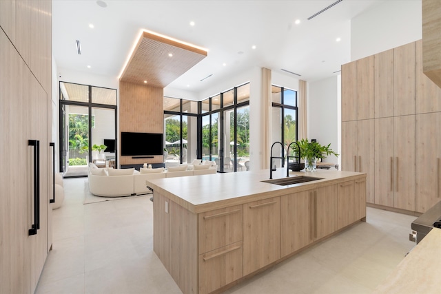 kitchen with an island with sink, light brown cabinetry, and sink