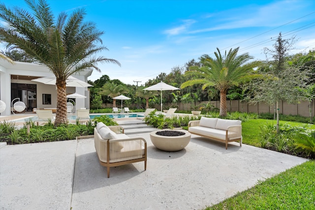 view of patio featuring a fenced in pool and an outdoor living space with a fire pit