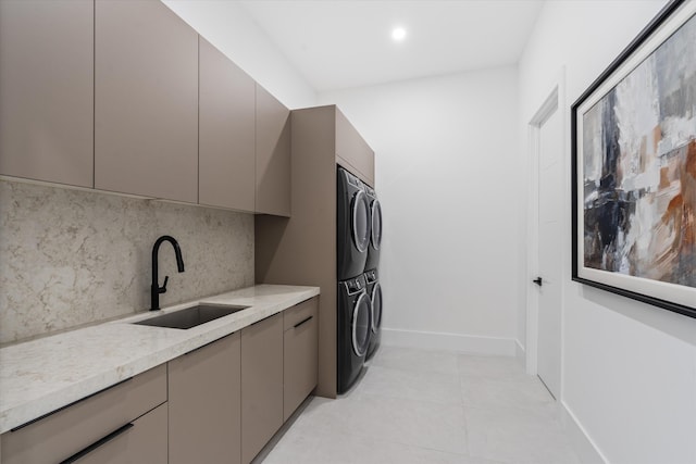 washroom with stacked washer and clothes dryer, cabinets, sink, and light tile patterned flooring