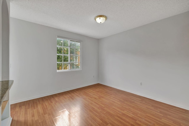 spare room with a textured ceiling and light hardwood / wood-style flooring