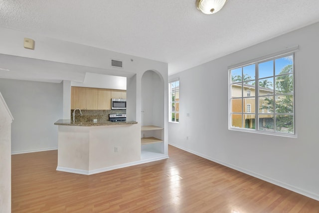 kitchen featuring a textured ceiling, light brown cabinetry, a wealth of natural light, and light hardwood / wood-style flooring